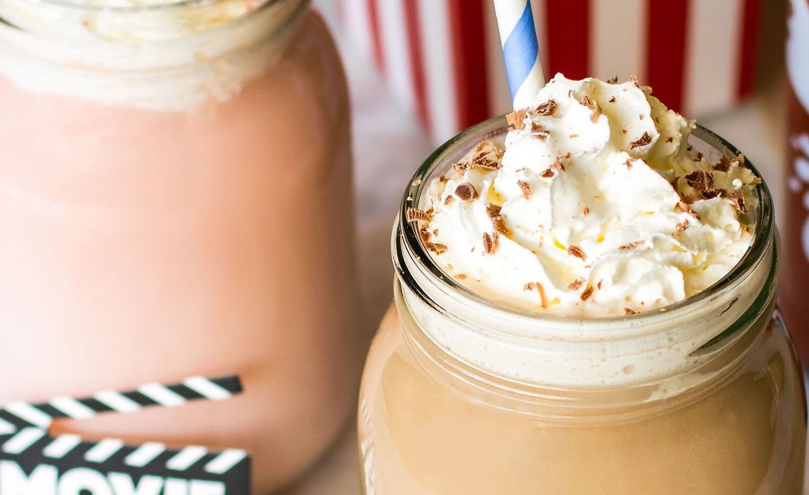 Banana and Strawberry milkshakes in glass jars with added fresh fruit, and Crusha milkshake bottles in the background.